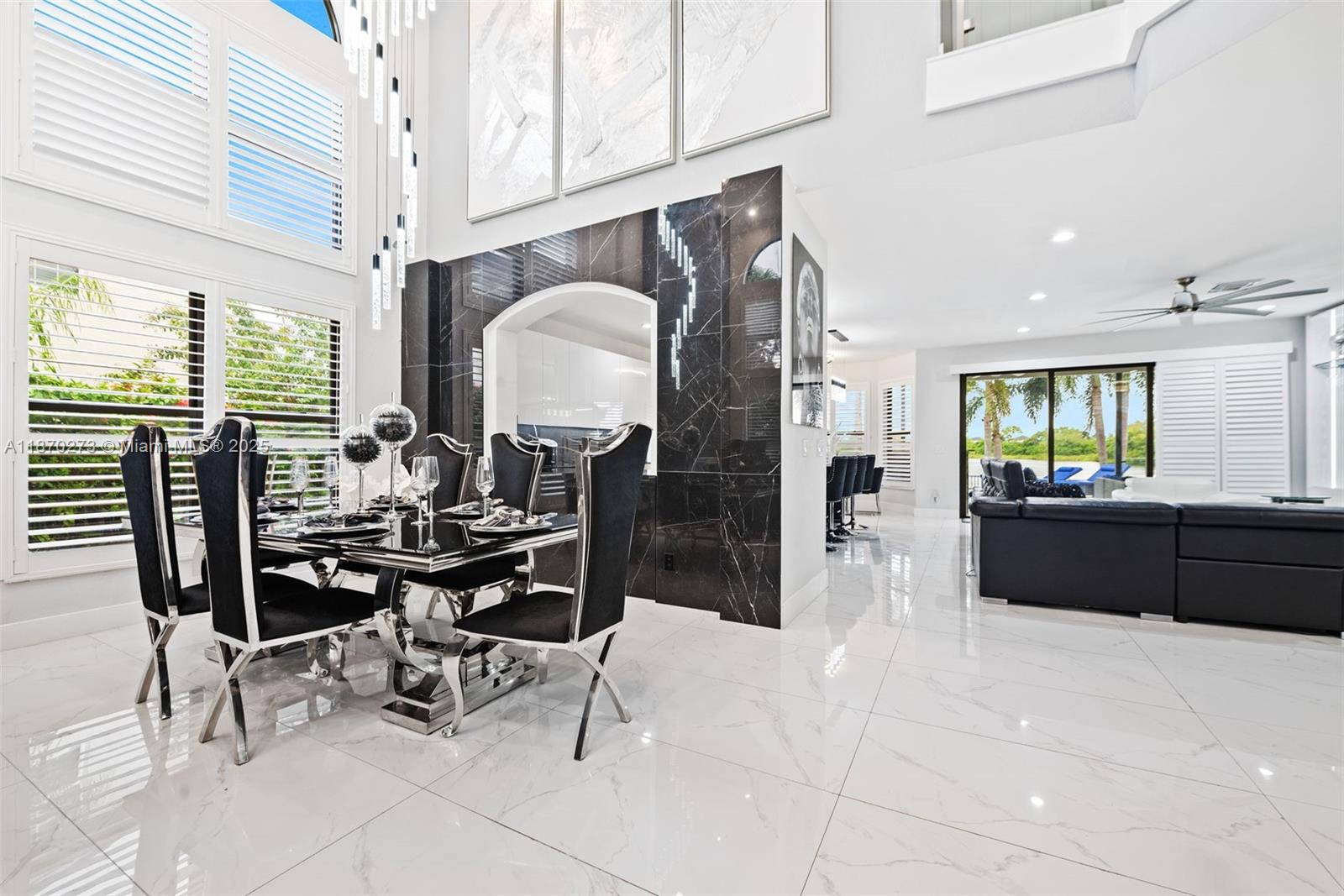 A dining area with a black marble wall, glass table, and white tile flooring — 3591 SW 177th Ave, Miramar FL 33029, MIRAMAR, FL