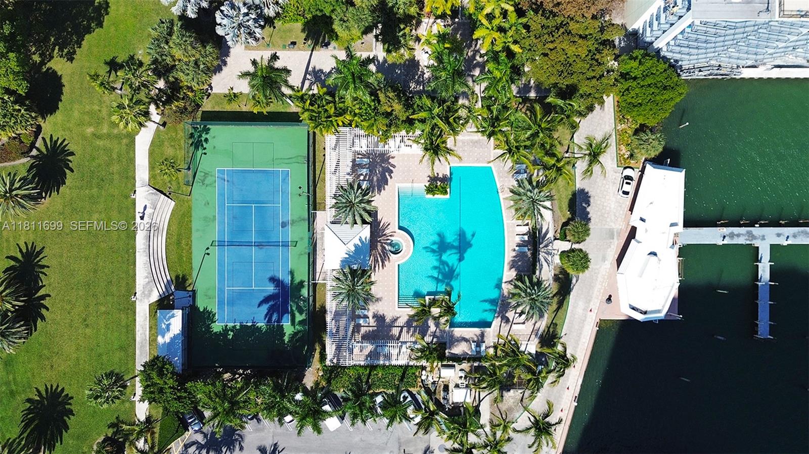 An aerial view shows a tennis court, swimming pool, and boat dock near water — 770 NE 69th St # 6C, Miami FL 33138, MIAMI, FL