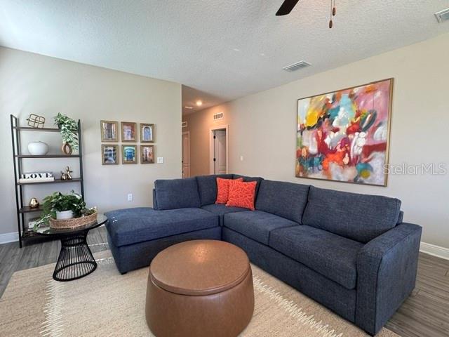 A living room features a dark blue sectional sofa, a round ottoman, and wall art — 7951 RUMNEY LANE, REUNION, FL