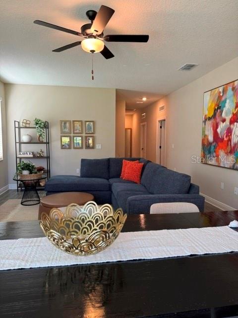 A living room features a dark blue sectional sofa, a ceiling fan, and wall art — 7951 RUMNEY LANE, REUNION, FL