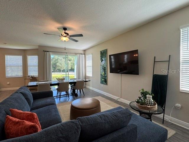 A living room features a blue sectional sofa, a dining area, and a wall-mounted television — 7951 RUMNEY LANE, REUNION, FL