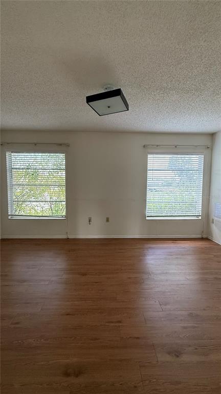 An empty room with wood-look flooring, two windows with blinds, and a square ceiling light — 201 SAN MARCO AVENUE UNIT 2, NORTH PORT, FL
