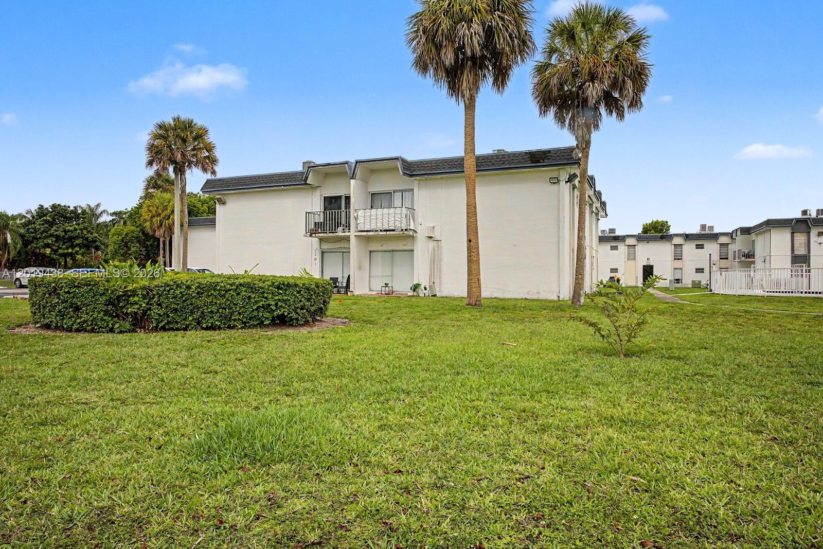 A playground with a blue shade canopy sits on a grassy field under a sky — 7256 SW 94th Pl # A8, Miami FL 33173, MIAMI, FL