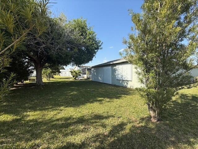 A grassy yard features a large tree and a light-colored house with vertical siding — 6715 Mar Pacifico, Fort Pierce FL 34951, FORT PIERCE, FL