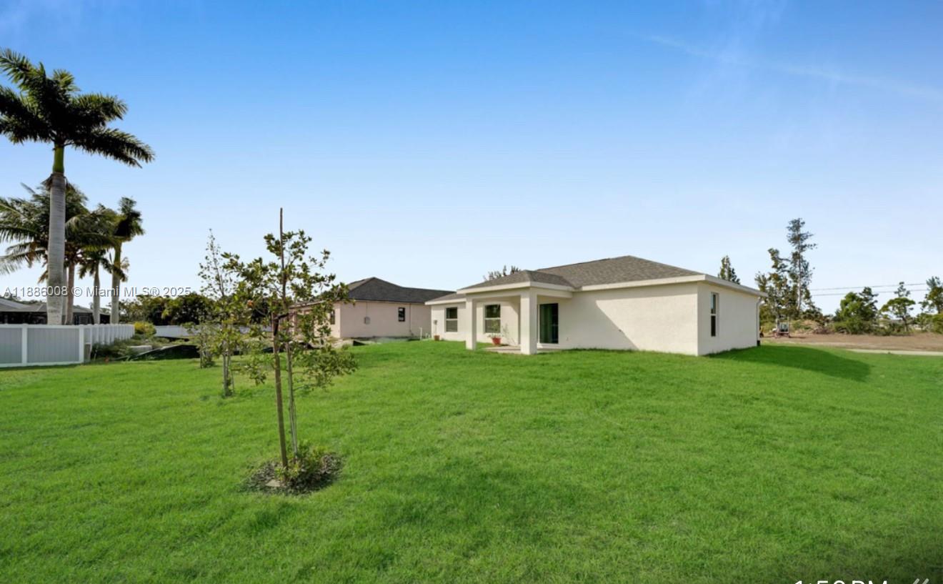 A view of the rear exterior of a single-story house with a large grassy yard — 4217 NE 23rd Pl, Cape Coral FL 33909, CAPE CORAL, FL