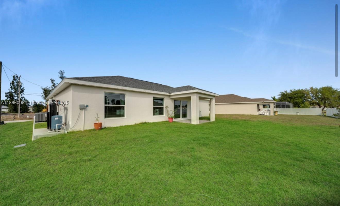 The rear exterior of a single-story house with a covered patio and a grassy yard — 4217 NE 23rd Pl, Cape Coral FL 33909, CAPE CORAL, FL