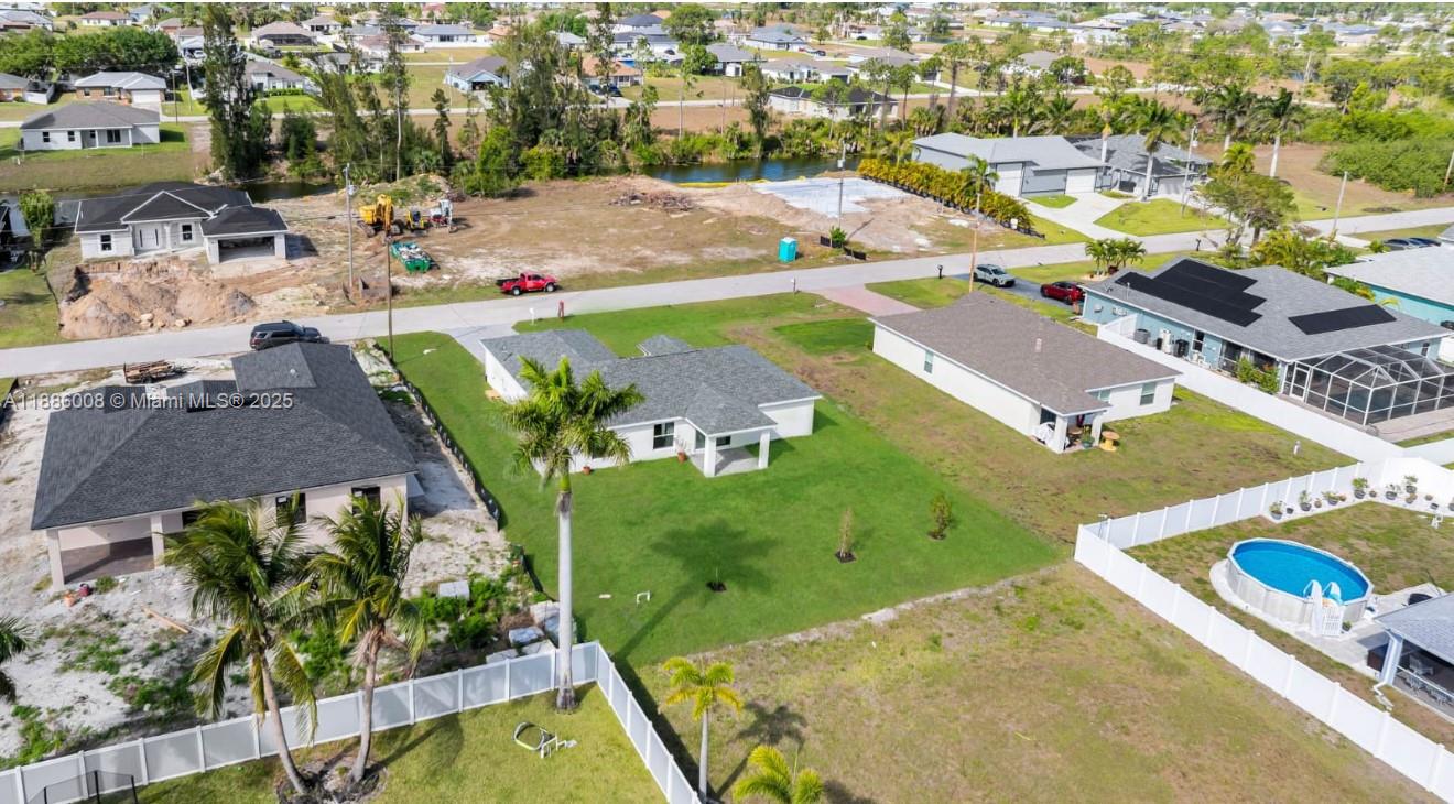 An aerial view shows several suburban houses, a vacant lot, and a fenced backyard with a pool — 4217 NE 23rd Pl, Cape Coral FL 33909, CAPE CORAL, FL