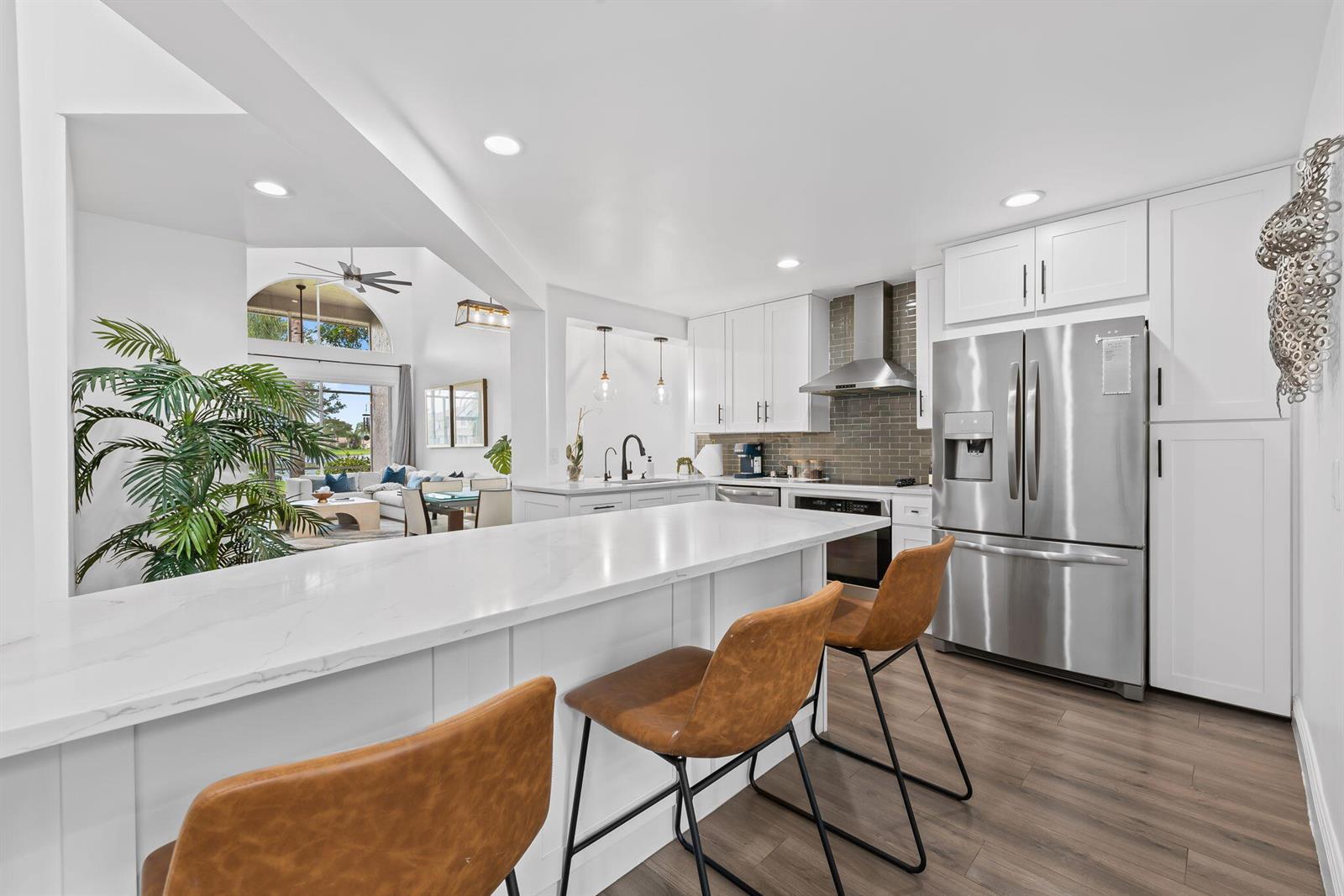 A modern kitchen features white cabinetry, a quartz island with bar stools, and stainless appliances — 9226 Boca Gardens Parkway, Boca Raton FL 33496, BOCA RATON, FL