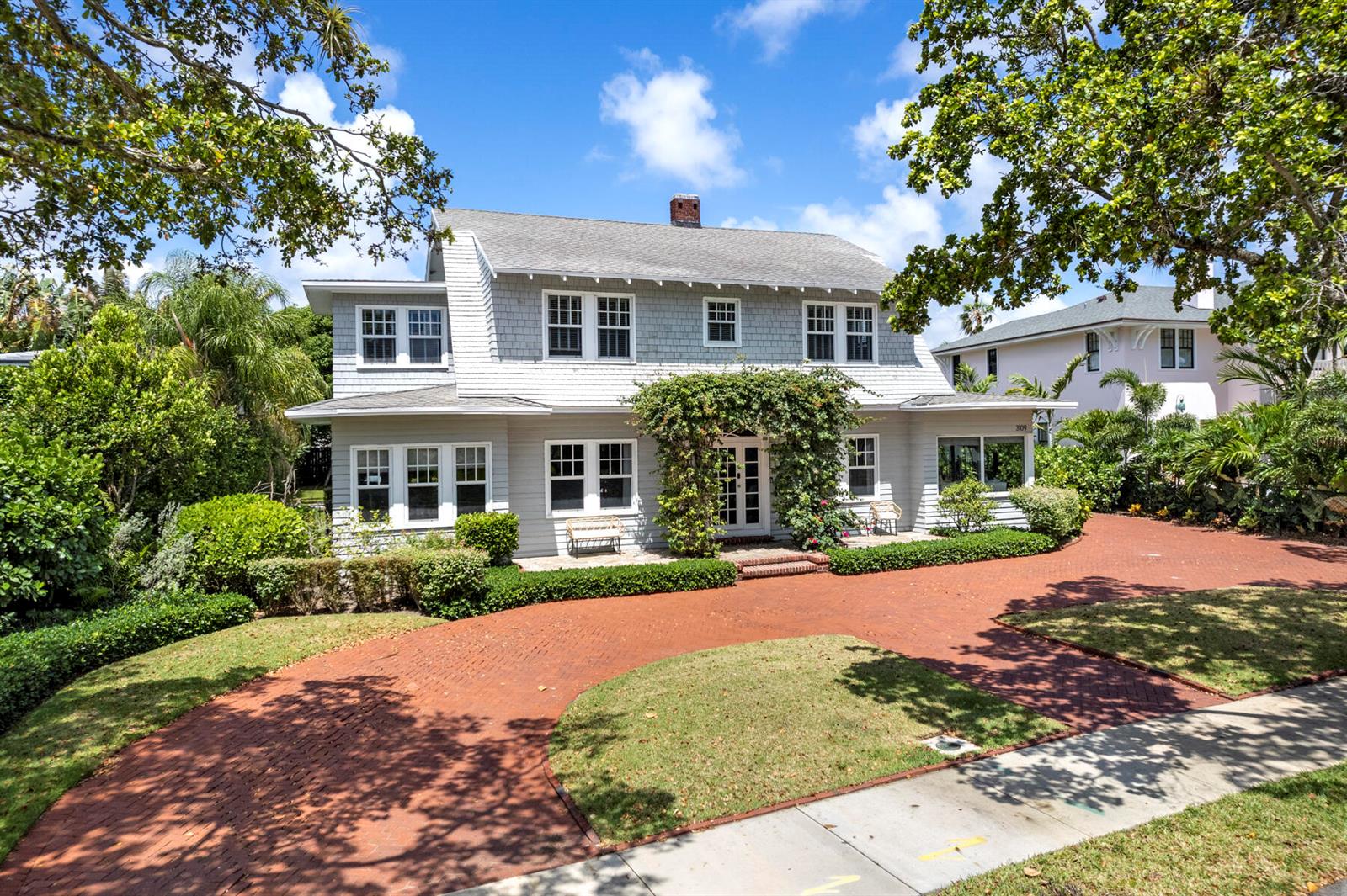 A two-story gray shingled house features a brick driveway and a vine-covered front entrance — 3109 Washington Road, West Palm Beach FL 33405, WEST PALM BEACH, FL
