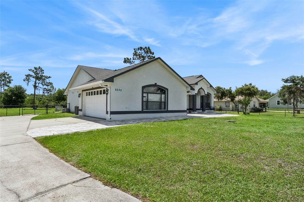 A single-story house with a white stucco exterior, a two-car garage, and a large lawn — 7035 BIG BEND DRIVE, ST CLOUD, FL