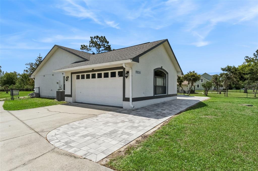 A single-story house with a white stucco exterior, a two-car garage, and a paved driveway — 7035 BIG BEND DRIVE, ST CLOUD, FL