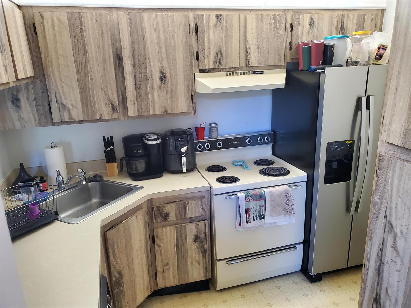 A kitchen features wood-grain cabinets, a white stove, a stainless steel refrigerator, and a sink — 629 Sea Pine Way # H3, FL 33415, FL