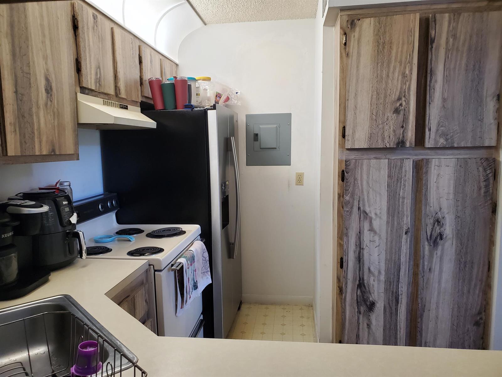 A kitchen features wood-look cabinets, a white stove, a stainless steel refrigerator, and a sink — 629 Sea Pine Way # H3, FL 33415, FL