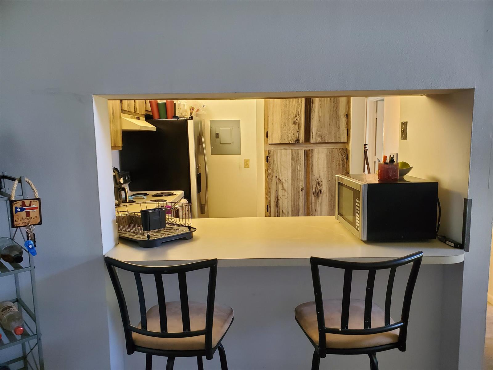 A kitchen pass-through window features a breakfast bar with two chairs and a microwave — 629 Sea Pine Way # H3, FL 33415, FL