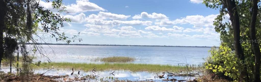 A view of a lake from a wooded shoreline under a blue sky with clouds — LAKE REEDY BOULEVARD N, FROSTPROOF, FL
