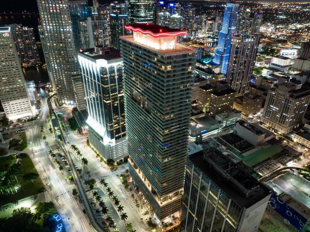 An aerial night view of a modern skyscraper with a distinctive red-lit roof in Miami — 50 Biscayne Boulevard, Miami FL 33132, MIAMI, FL