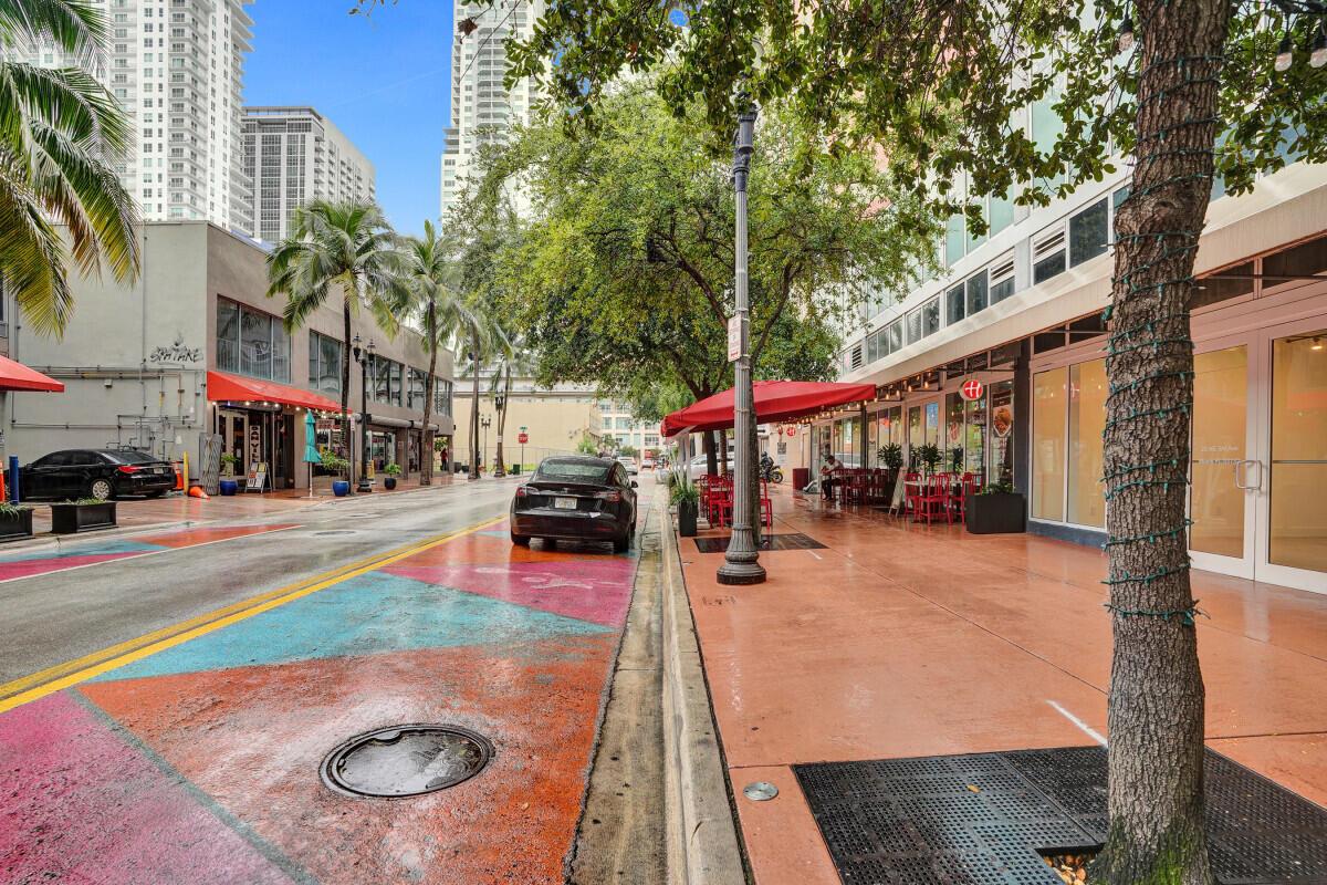 A street-level view of a city sidewalk with outdoor dining and colorful road markings — 50 Biscayne Boulevard, Miami FL 33132, MIAMI, FL