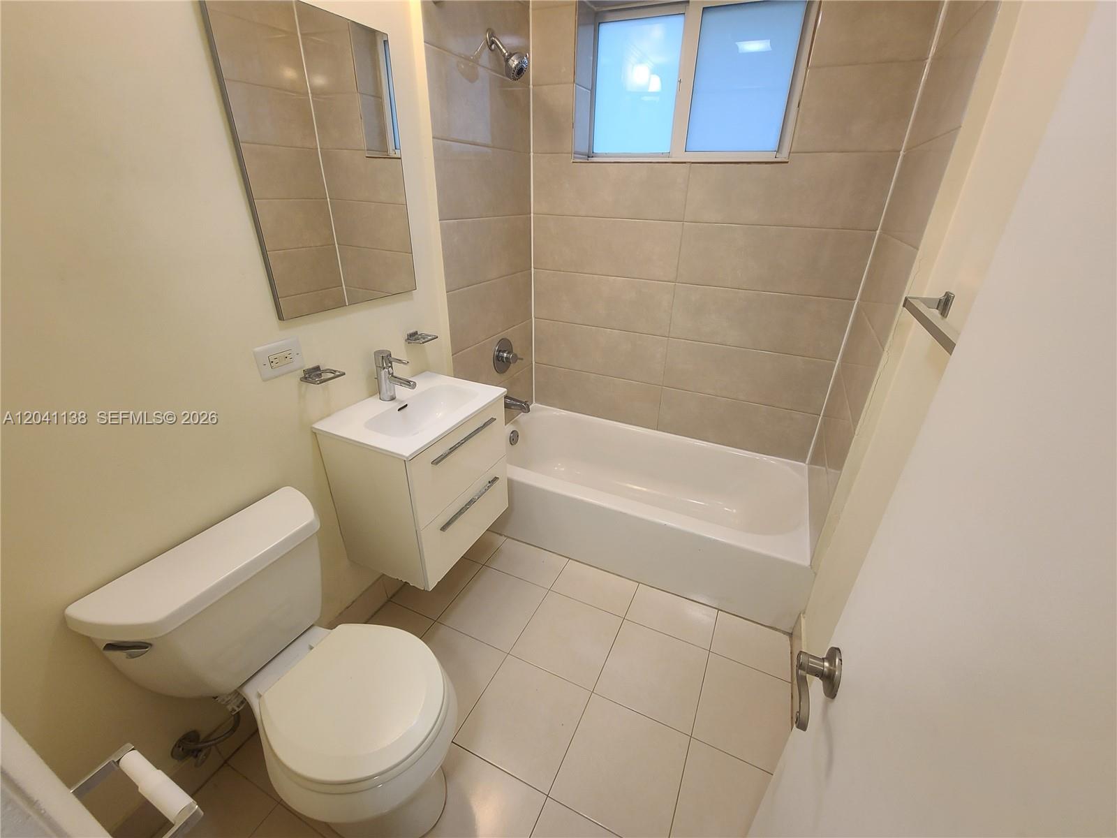 A bathroom features a white vanity, a toilet, and a tiled shower-tub combination — 220 Collins Ave # 3B, Miami Beach FL 33139, MIAMI BEACH, FL