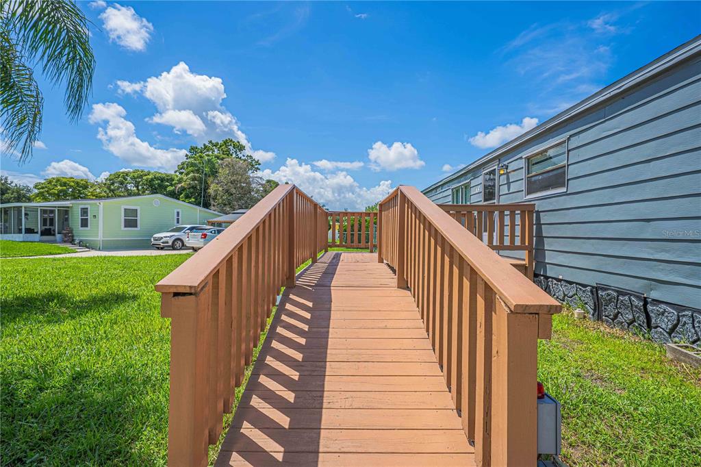 A wooden wheelchair ramp leads to the entrance of a blue mobile home — 1148 MARY FRANCES DRIVE, KISSIMMEE, FL