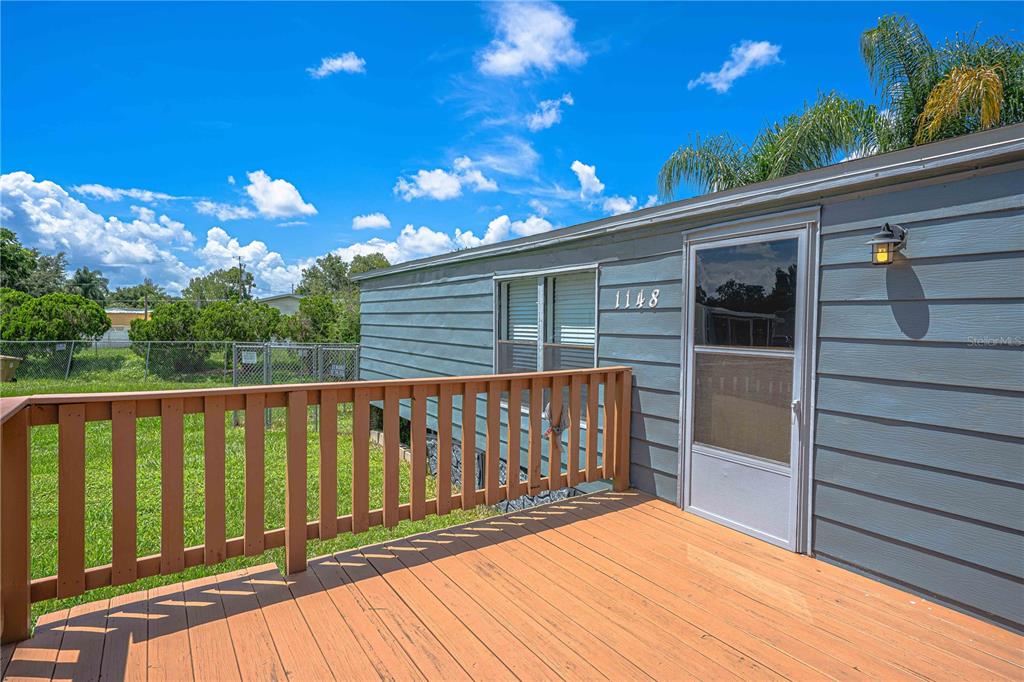 A wooden deck with a railing sits outside the blue-sided exterior of a home — 1148 MARY FRANCES DRIVE, KISSIMMEE, FL