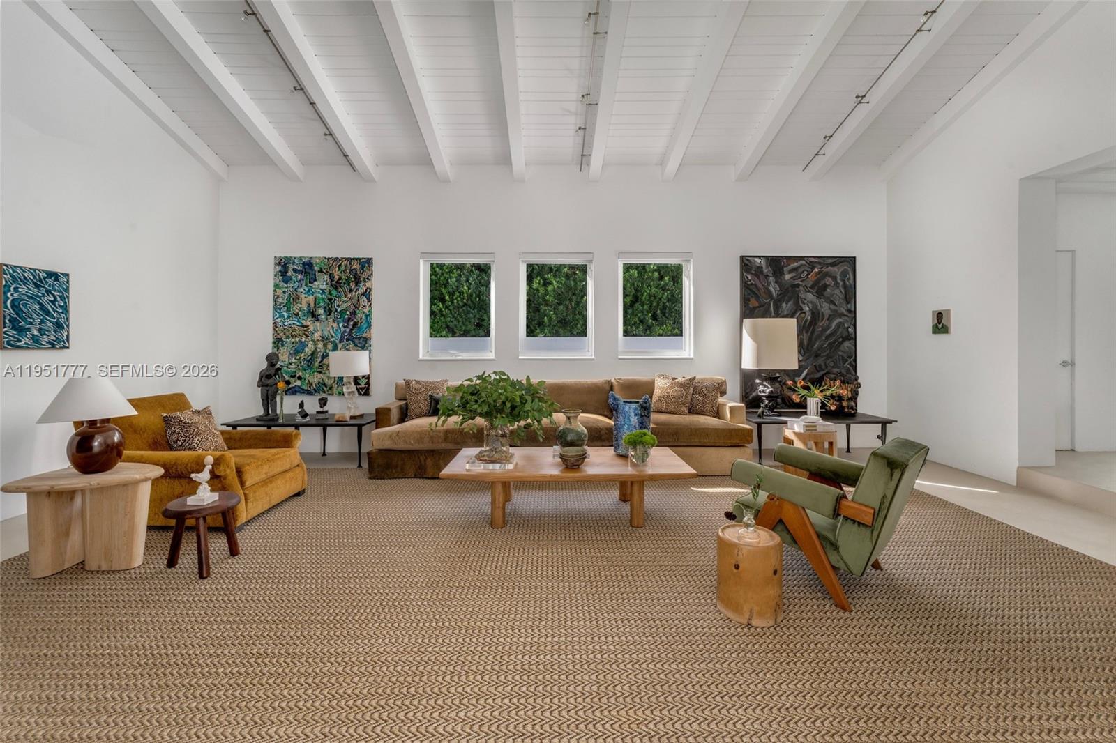 A spacious living room features a vaulted beamed ceiling, white walls, and a large rug — 3325 Pine Tree Dr, Miami Beach FL 33140, MIAMI BEACH, FL