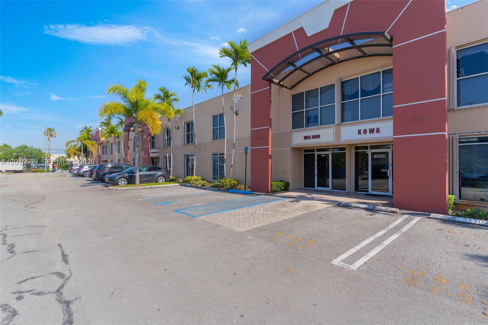 An exterior view of a commercial building with a parking lot and palm trees — 8216 NW 30th Ter, Doral FL 33122, DORAL, FL