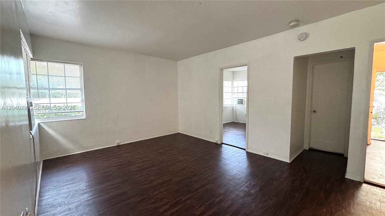 An empty room features dark wood-look flooring, white walls, and a doorway leading to another room — 4410 NE 2nd Ave # 4410, Miami FL 33137, MIAMI, FL