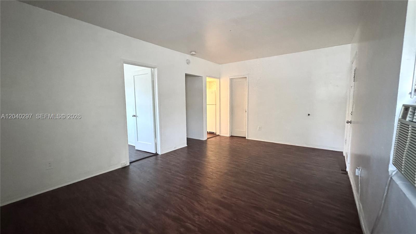 An empty room features white walls, dark wood-look flooring, and several interior doorways — 4410 NE 2nd Ave # 4410, Miami FL 33137, MIAMI, FL