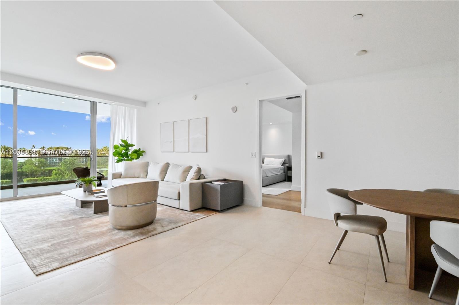 A bright living room features a beige sofa, round chair, and balcony with outdoor views — 10203 Collins Ave # 305, Bal Harbour FL 33154, BAL HARBOUR, FL