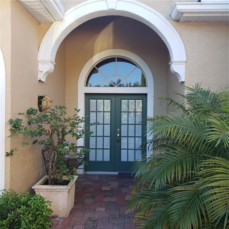 A front entryway features double green doors with glass panes under a white arched portico — 5125 MAGNOLIA POND DRIVE, SARASOTA, FL