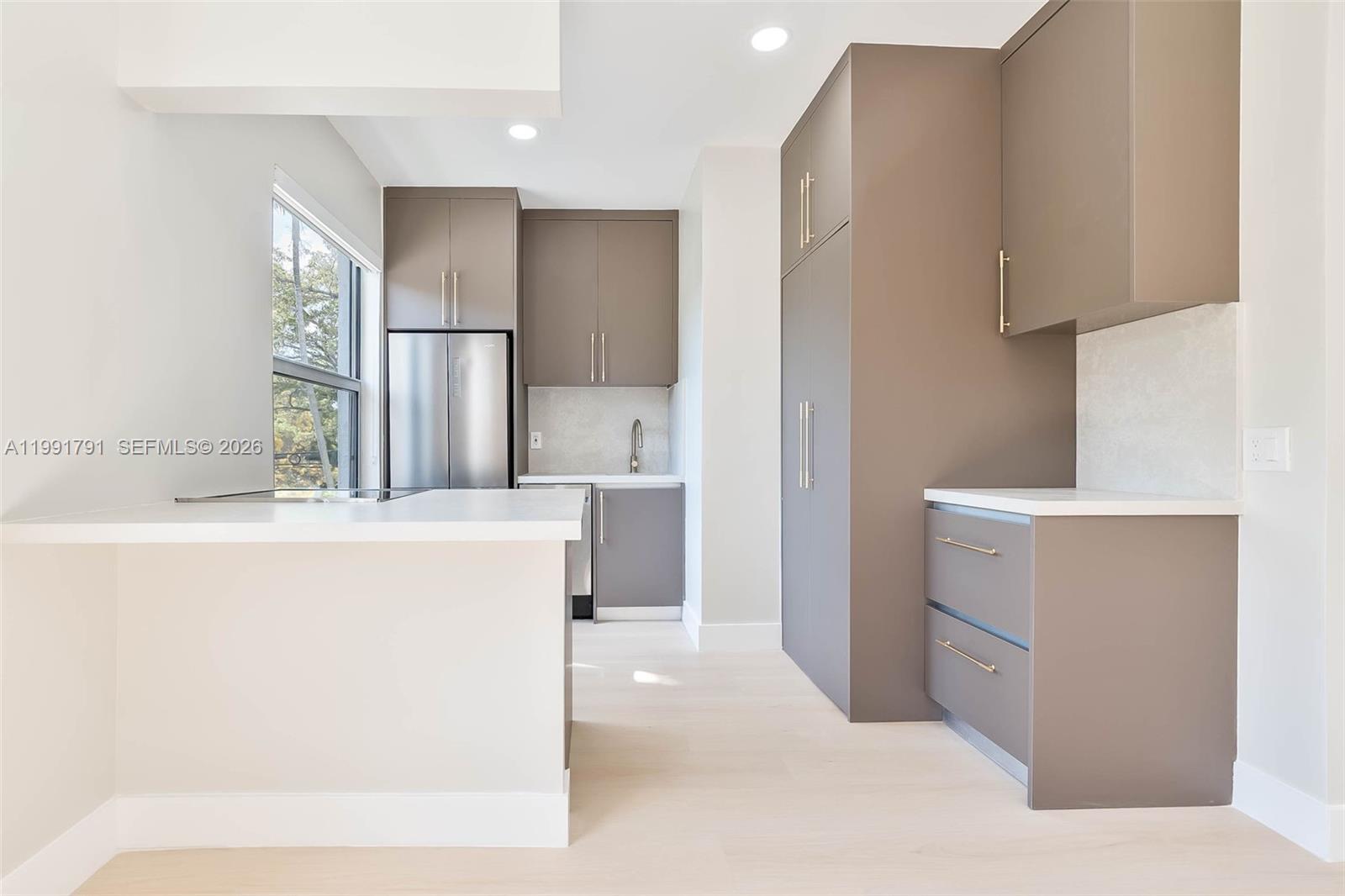 A modern kitchen features gray flat-panel cabinetry, white countertops, and stainless steel appliances — 694 NE 76th St # 6, Miami FL 33138, MIAMI, FL