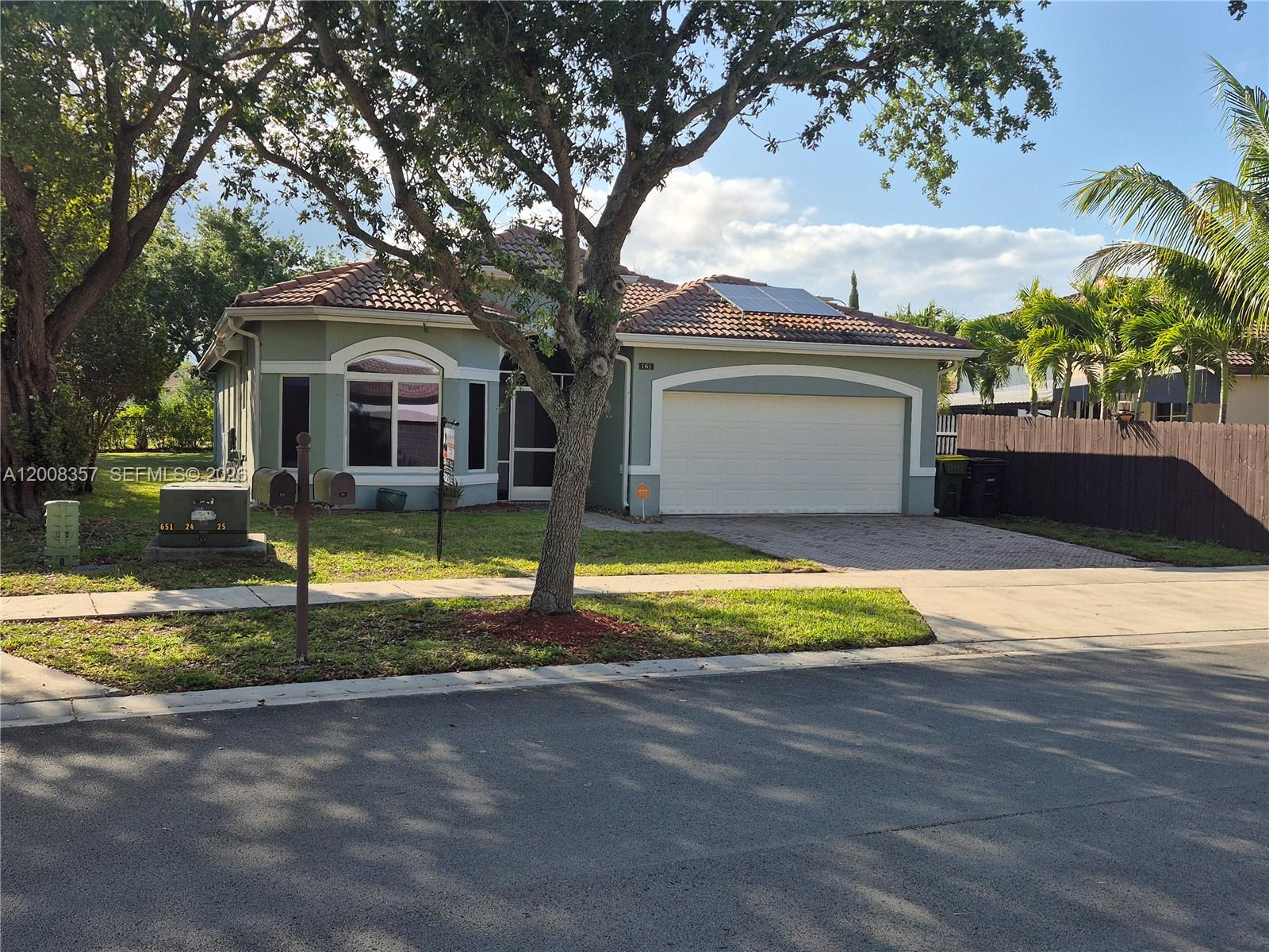 A single-story house with a tiled roof, garage, and front yard under a large tree — 161 SE 22nd Ter, Homestead FL 33033, HOMESTEAD, FL