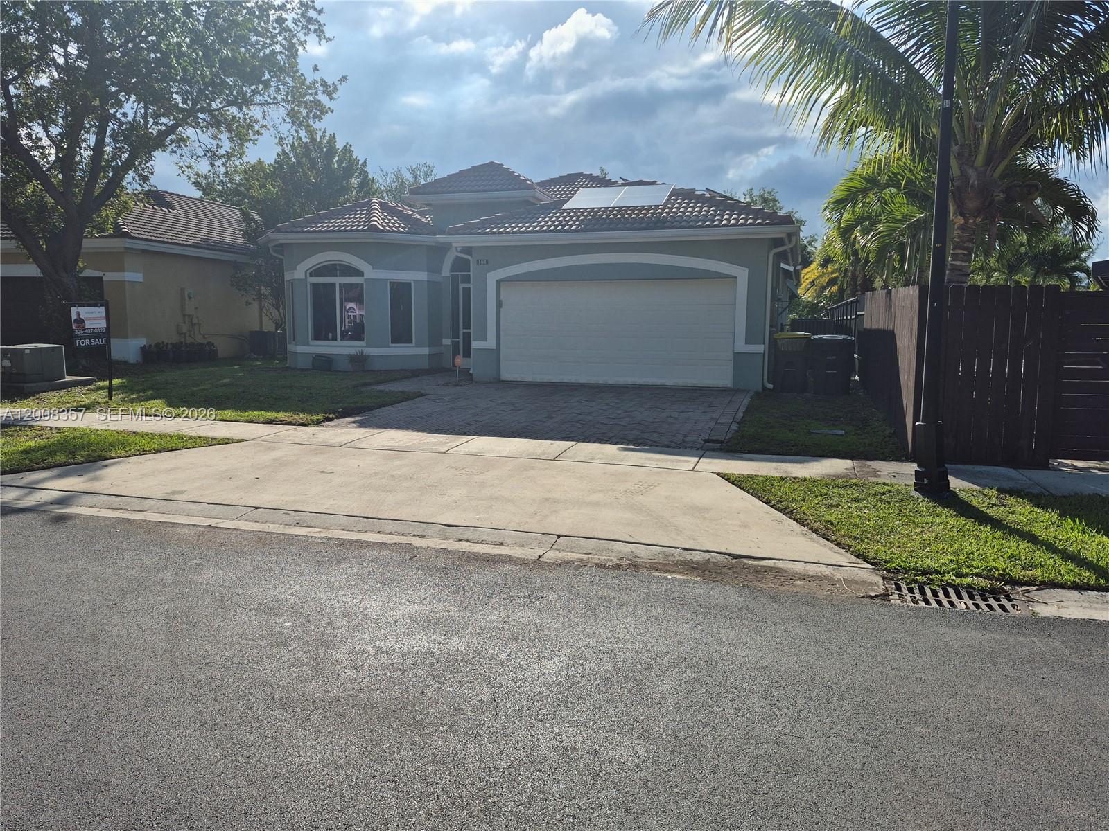 A single-story house with a tiled roof, solar panels, and a paved driveway — 161 SE 22nd Ter, Homestead FL 33033, HOMESTEAD, FL
