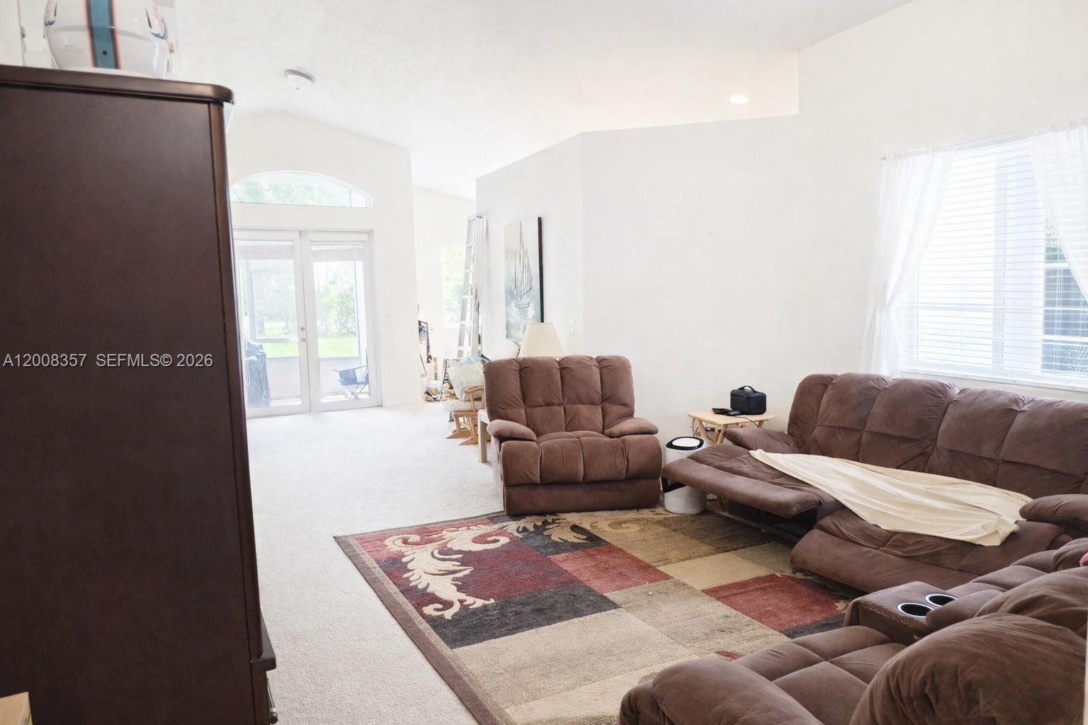A living room features brown reclining furniture, a patterned area rug, and glass patio doors — 161 SE 22nd Ter, Homestead FL 33033, HOMESTEAD, FL