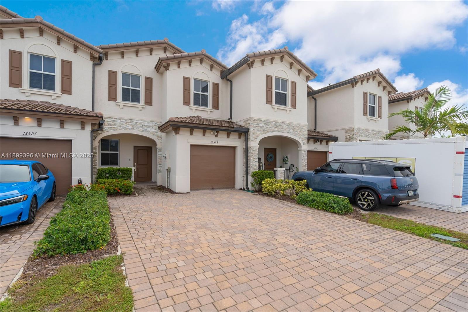 A row of multi-story townhouses features stucco facades, stone accents, and paved driveways — 12523 NW 24th Ave, Miami FL 33167, MIAMI, FL