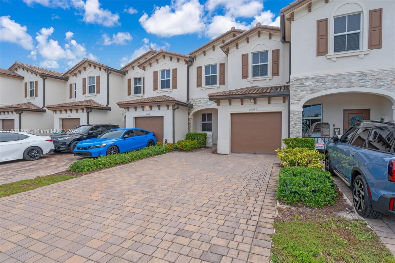 A row of two-story townhomes with paved driveways and parked cars under a blue sky — 12523 NW 24th Ave, Miami FL 33167, MIAMI, FL