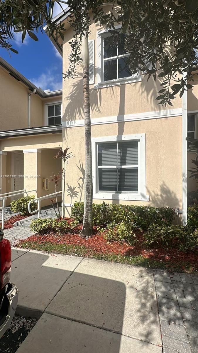 A two-story tan stucco townhouse exterior features a palm tree and a front entrance walkway — 2819 SE 1st Dr # 9, Homestead FL 33033, HOMESTEAD, FL