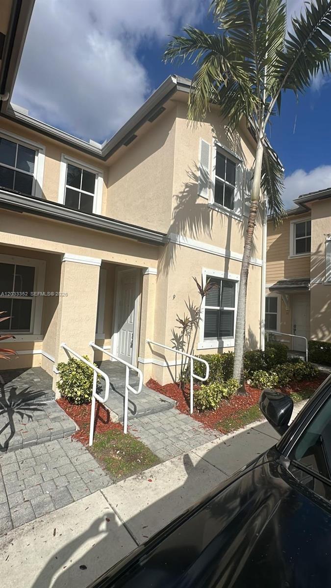 A two-story tan stucco townhouse features a front entrance with white metal handrails — 2819 SE 1st Dr # 9, Homestead FL 33033, HOMESTEAD, FL