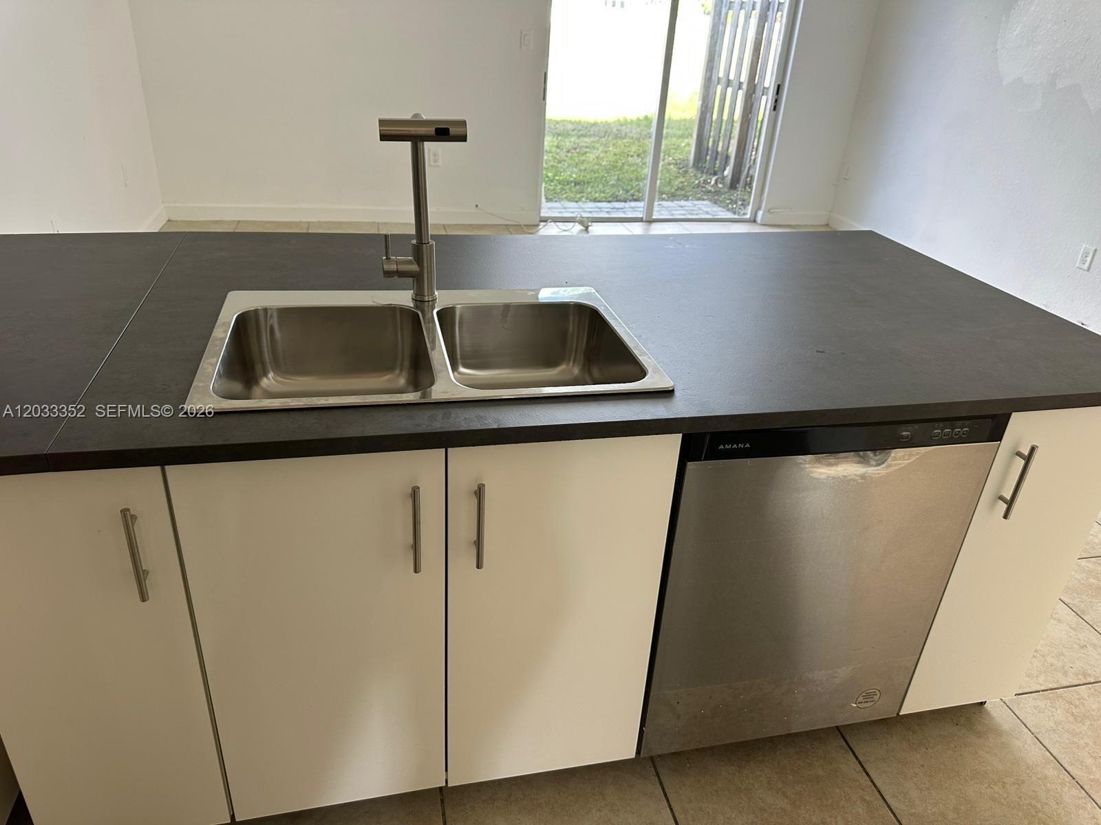 A kitchen island features a stainless steel double sink, faucet, and an Amana dishwasher — 2819 SE 1st Dr # 9, Homestead FL 33033, HOMESTEAD, FL