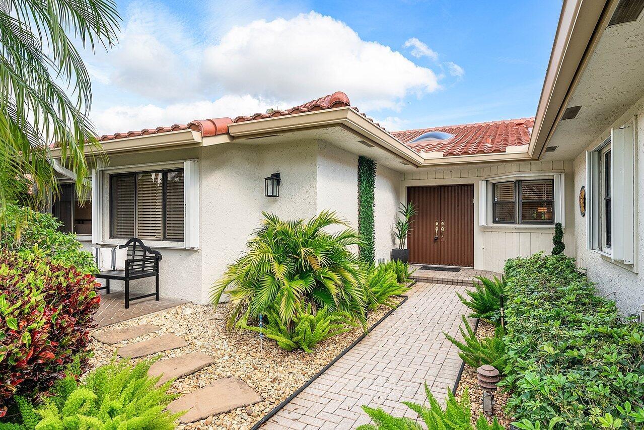 A paved walkway leads to the front entrance of a house with a tiled roof — 18 Bristol Lane, Boynton Beach FL 33436, BOYNTON BEACH, FL