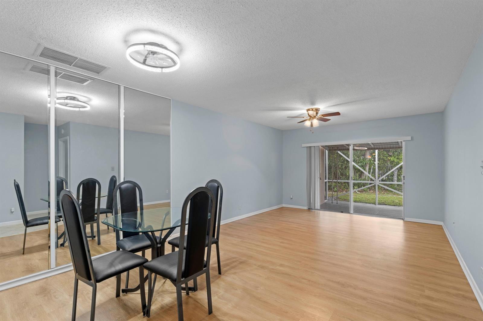A dining area with a glass table, black chairs, mirrored closet doors, and sliding glass doors — 8555 Bella Vista Drive # 86, Boca Raton FL 33433, BOCA RATON, FL