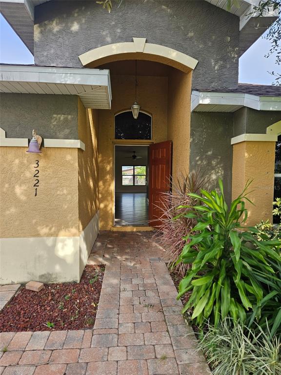The exterior of a house features a stone-paved walkway leading to an open front door — 3221 SW SANTA BARBARA PL, CAPE CORAL, FL
