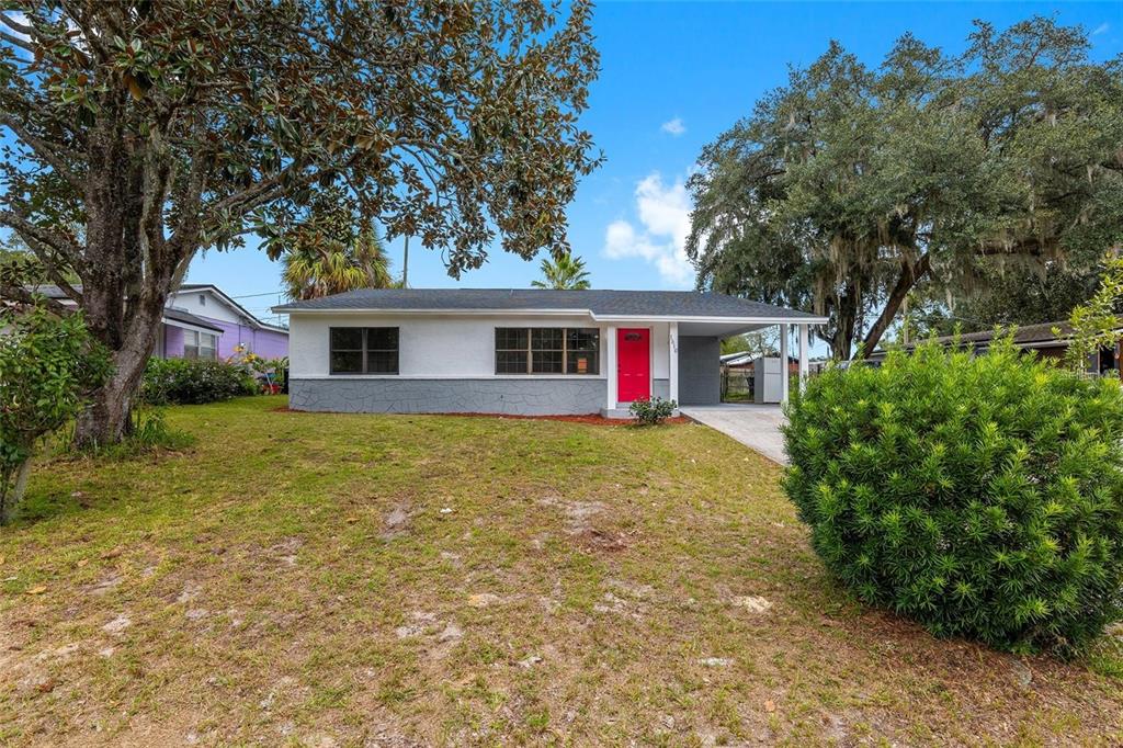 A single-story house with a white and gray exterior, a red front door, and a carport — 1510 SE 14TH AVENUE, GAINESVILLE, FL