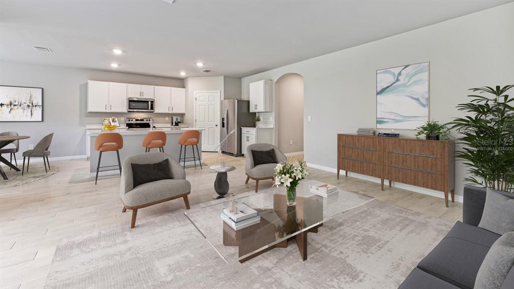 This open-concept living room features a kitchen with white cabinetry and a dining area — 16313 JUAREZ CIRCLE, PUNTA GORDA, FL