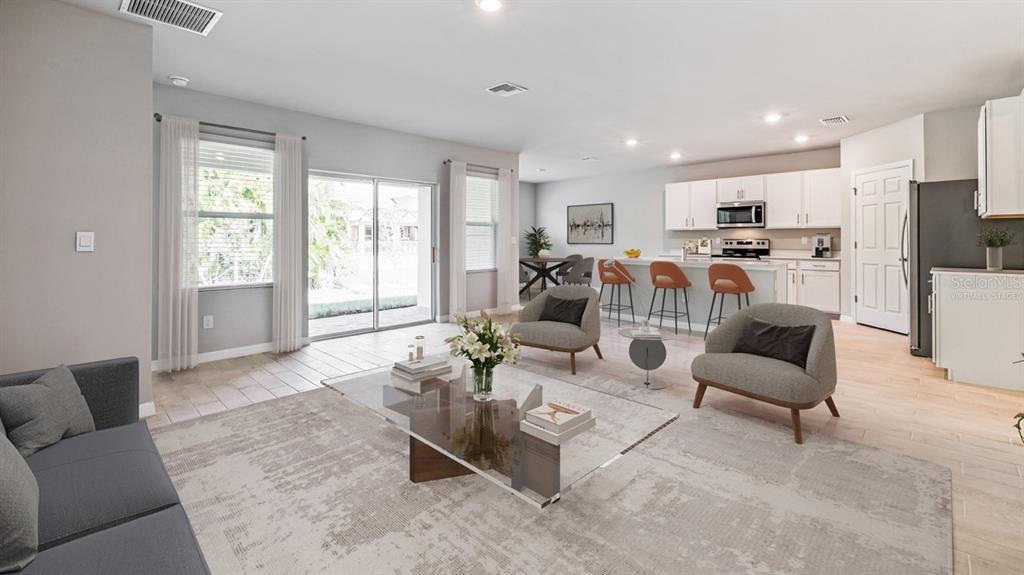 A living room and kitchen with light wood floors, white cabinets, and a glass coffee table — 16313 JUAREZ CIRCLE, PUNTA GORDA, FL