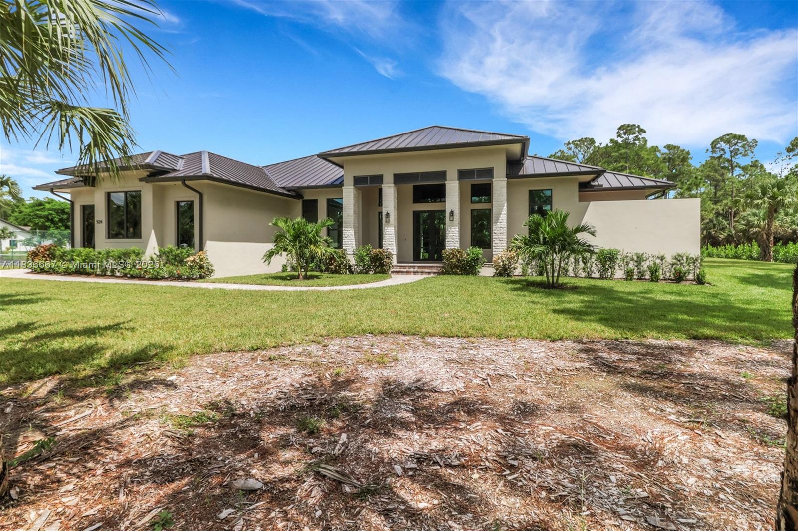 A single-story house with a metal roof, stucco walls, and stone accents sits on a lawn — 524 13th St Sw, Naples FL 34117, NAPLES, FL