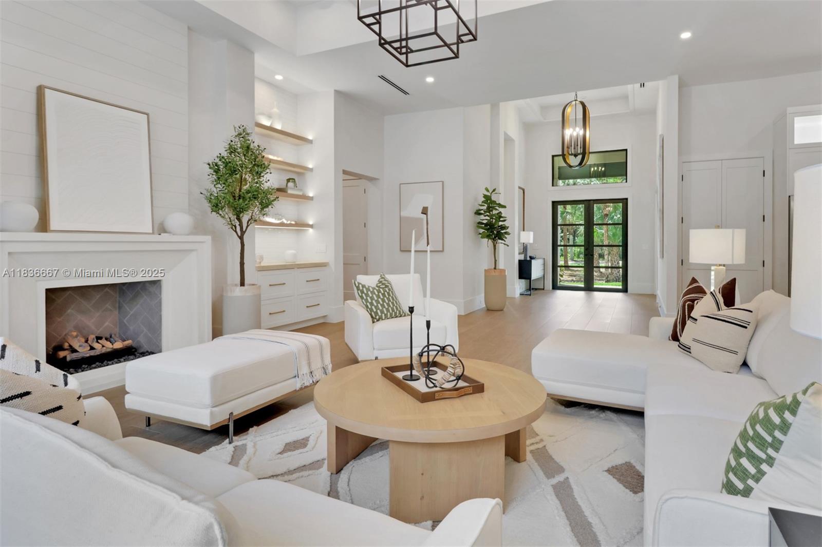 A bright living room features a fireplace, white furniture, a round coffee table, and shelving — 524 13th St Sw, Naples FL 34117, NAPLES, FL