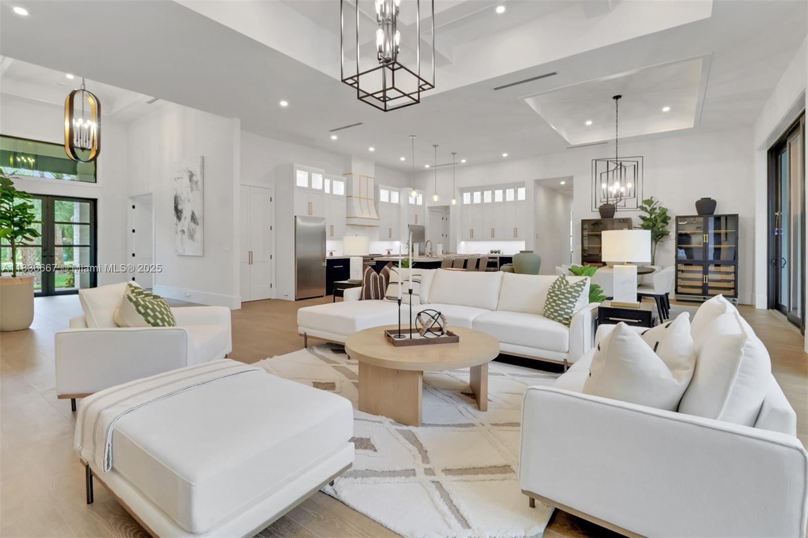 A bright, open-concept living room features white furniture, a round coffee table, and high ceilings — 524 13th St Sw, Naples FL 34117, NAPLES, FL