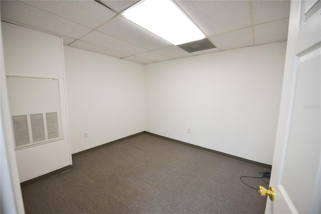 An empty office room features white walls, a drop ceiling, and gray carpeted flooring — 1200 N CENTRAL AVENUE UNIT 210, KISSIMMEE, FL