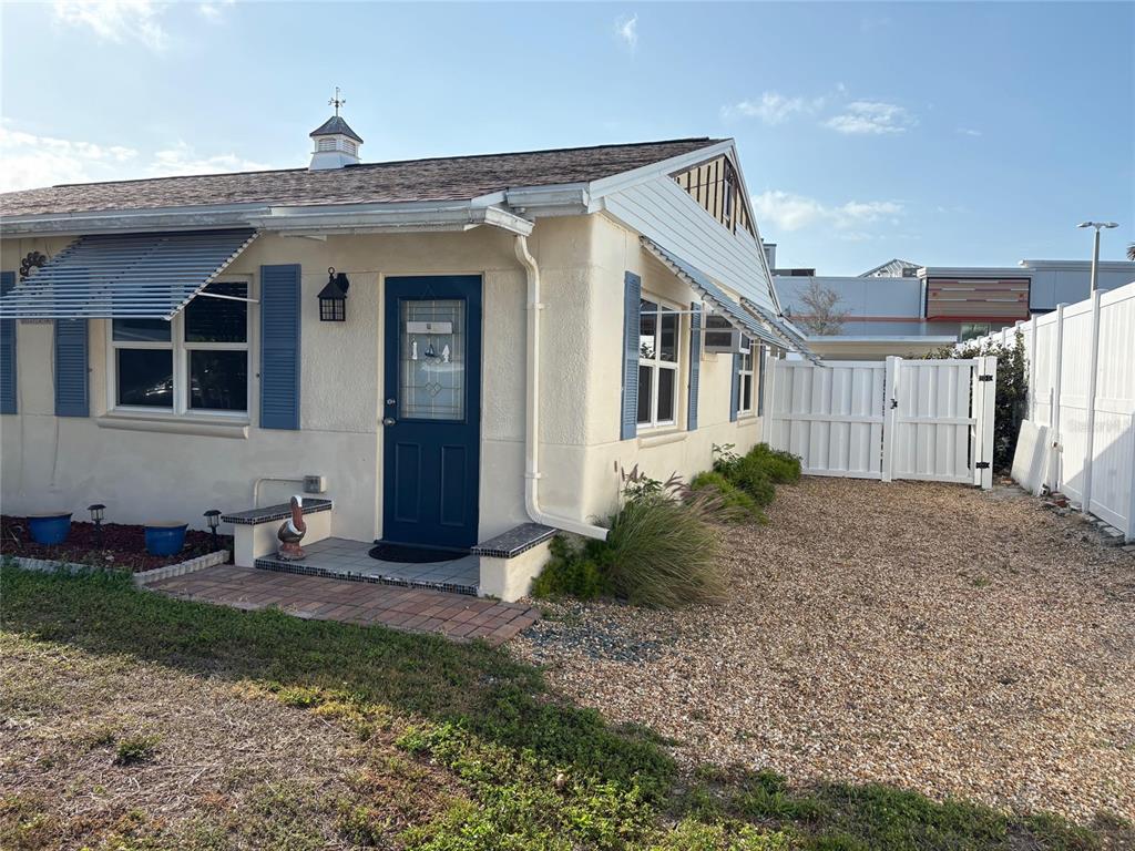 A single-story house with a blue door, blue shutters, and a gravel yard — 111 174TH AVENUE E, REDINGTON SHORES, FL
